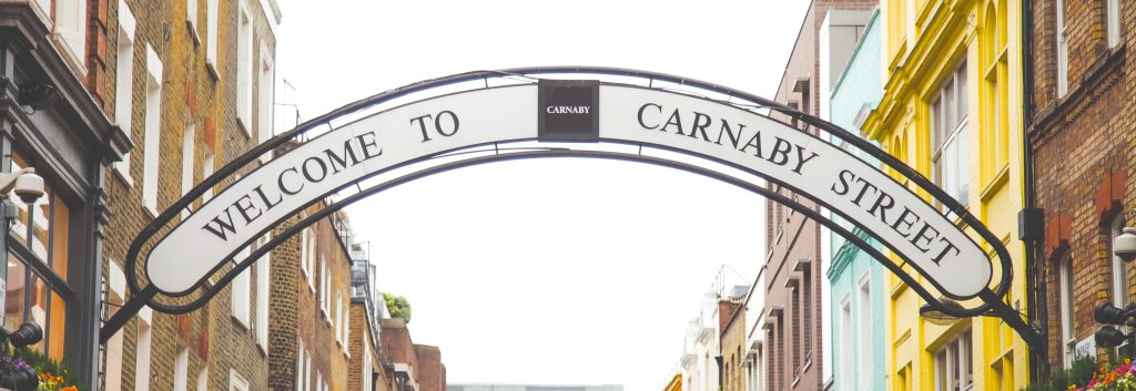 Welcome to Carnaby Street sign arch above colourful buildings in London.