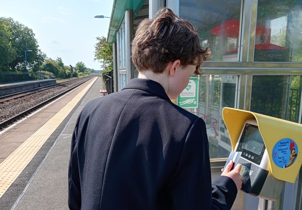 A secondary school pupil buying a ticket at a train station.