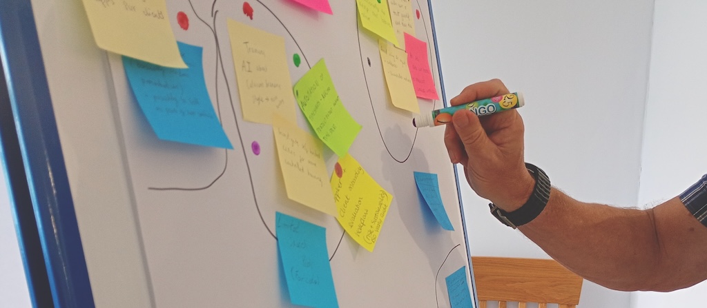 Hand with marker pen adding votes to a flip chart full of sticky notes with ideas from the discussions.