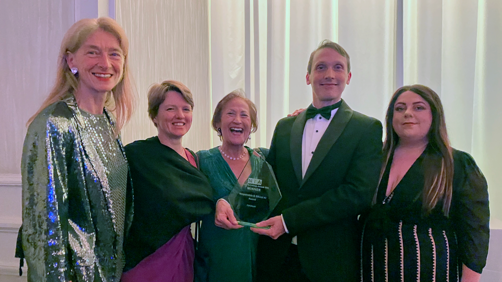 Five of the Calvium team in evening wear, smiling to camera and holding the award statue.