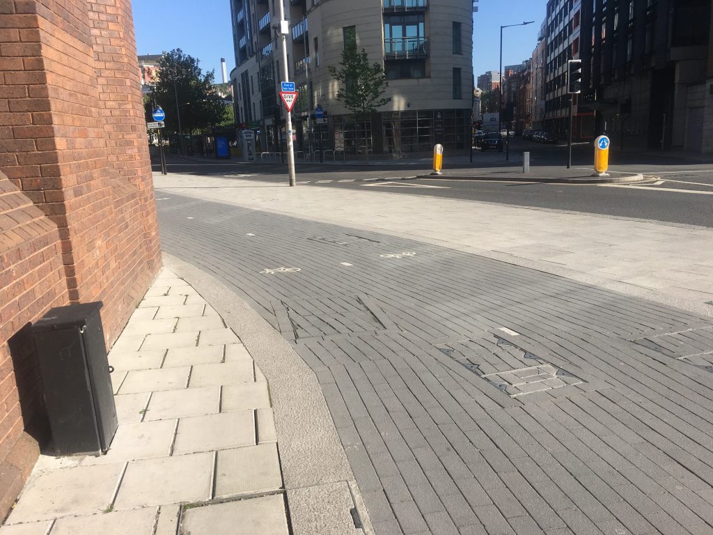 Photo of cycle path cutting off pedestrian paving at a building corner