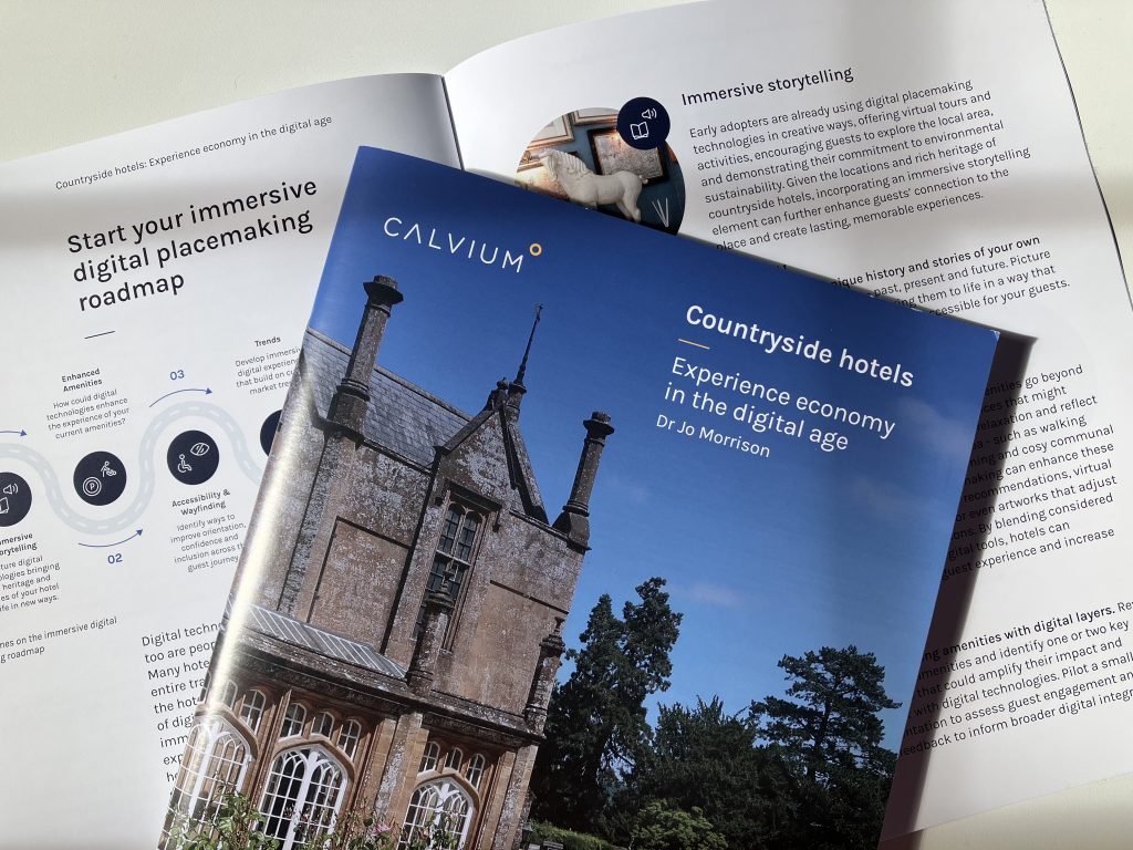 Report front cover with an historic hotel exterior and blue sky, lying on an open spread of the report.
