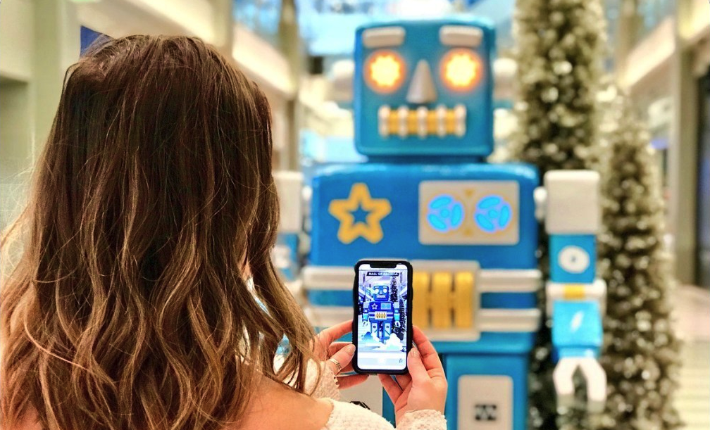 Person taking a photo with their phone of a robot in a shopping centre