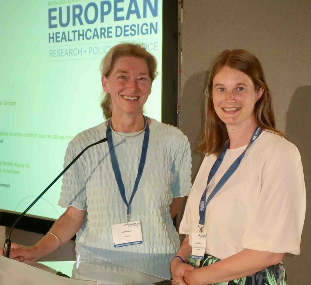 Jo Morrison and Louise Phillips stand together at a conference podium as they present 
