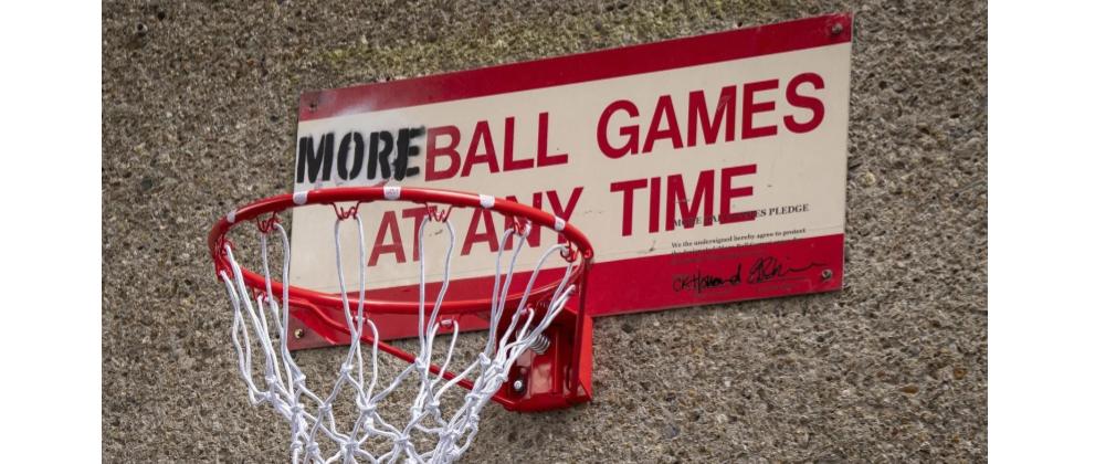 An amended 'No ball games at any time' sign - 'MORE' obscures the 'No', and a basketball hoop has been attached to the bottom, to make the sign a bounce-back board.