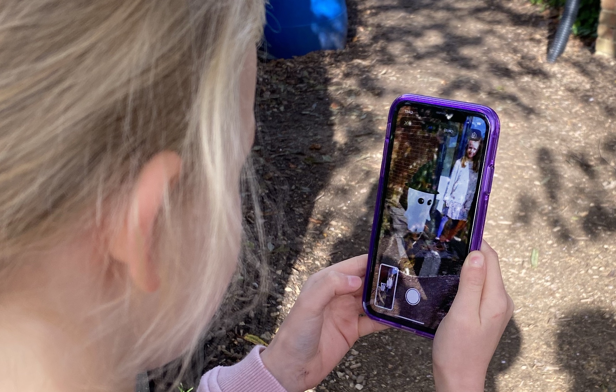 Child looking at phone, showing sister and friendly ghost on screen