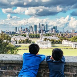 Two children looking over wall, over park to London skyline
