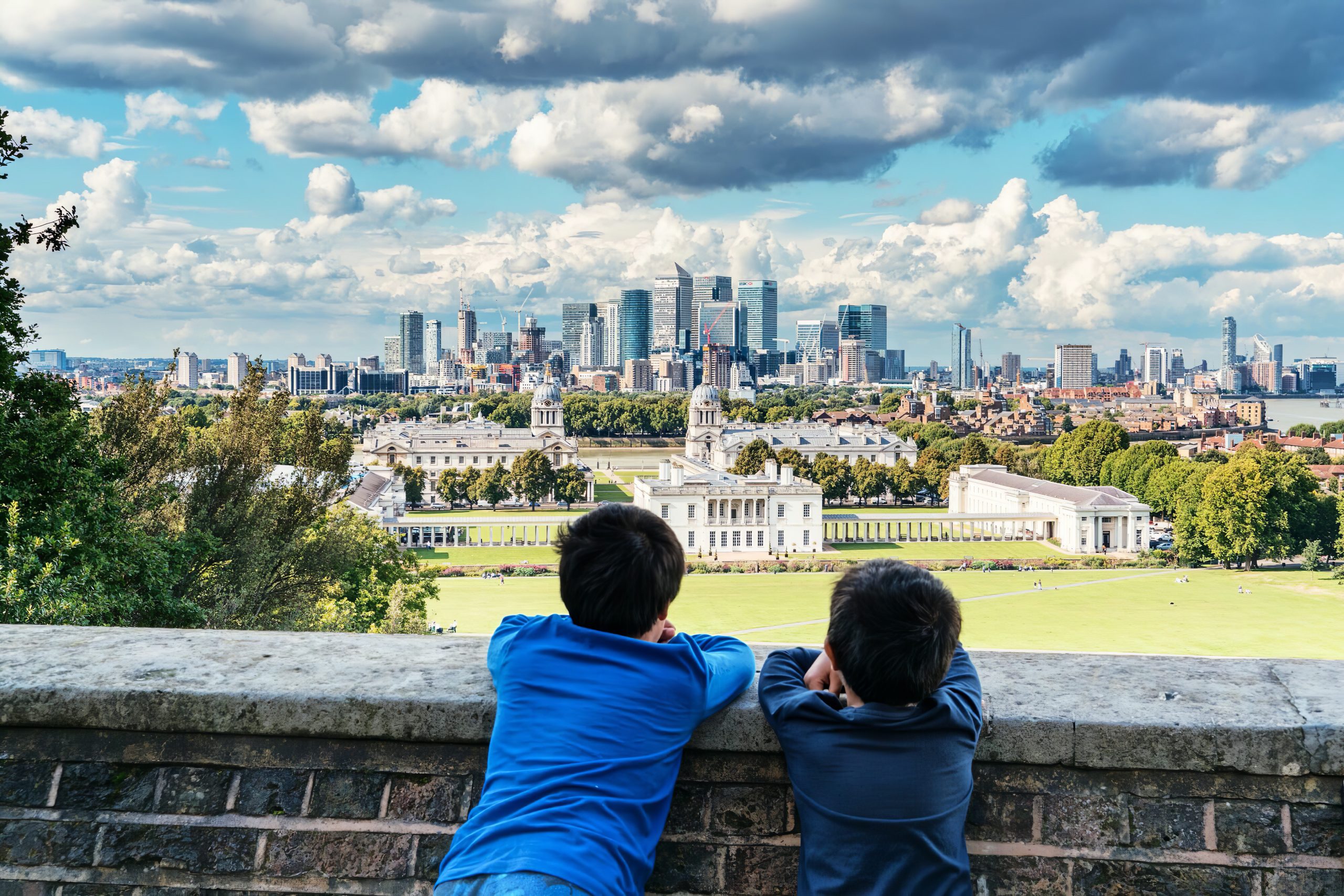 Two children looking over wall, over park to London skyline