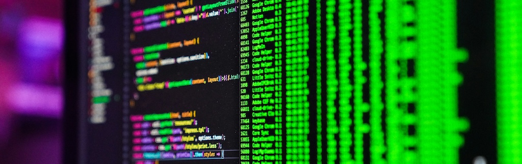 Computer monitor with lines of green code on right, and multicoloured code on left, all on a black background.