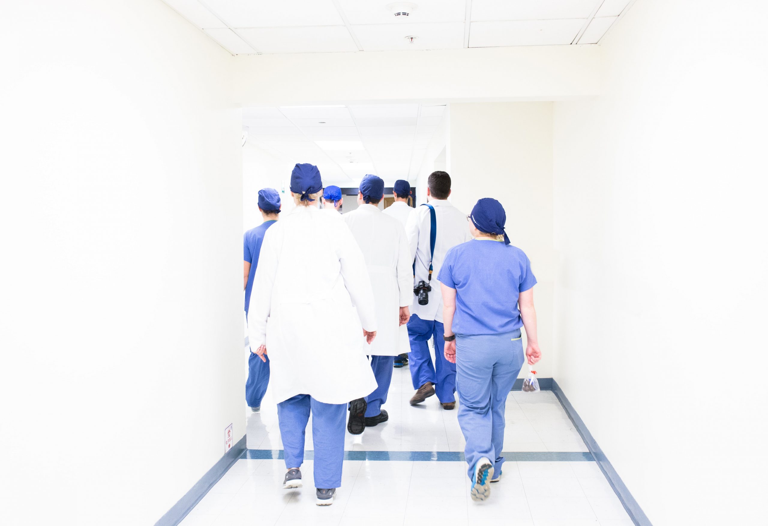 Image shows healthcare workers walking down a corridor in PPEscrubs