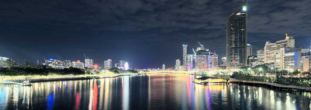 River through a city at night, with reflected lights in the water.