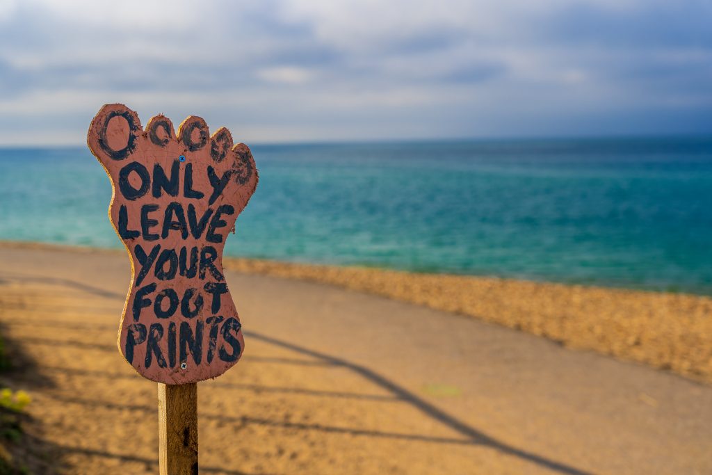 Photo of sign by beach saying 'Only leave your footprints'