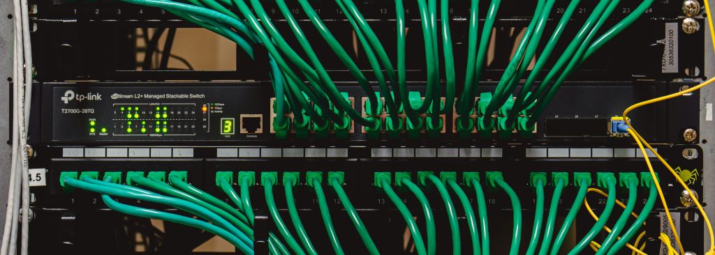Green ethernet cables plugged into and coming out of a bank of computer servers.